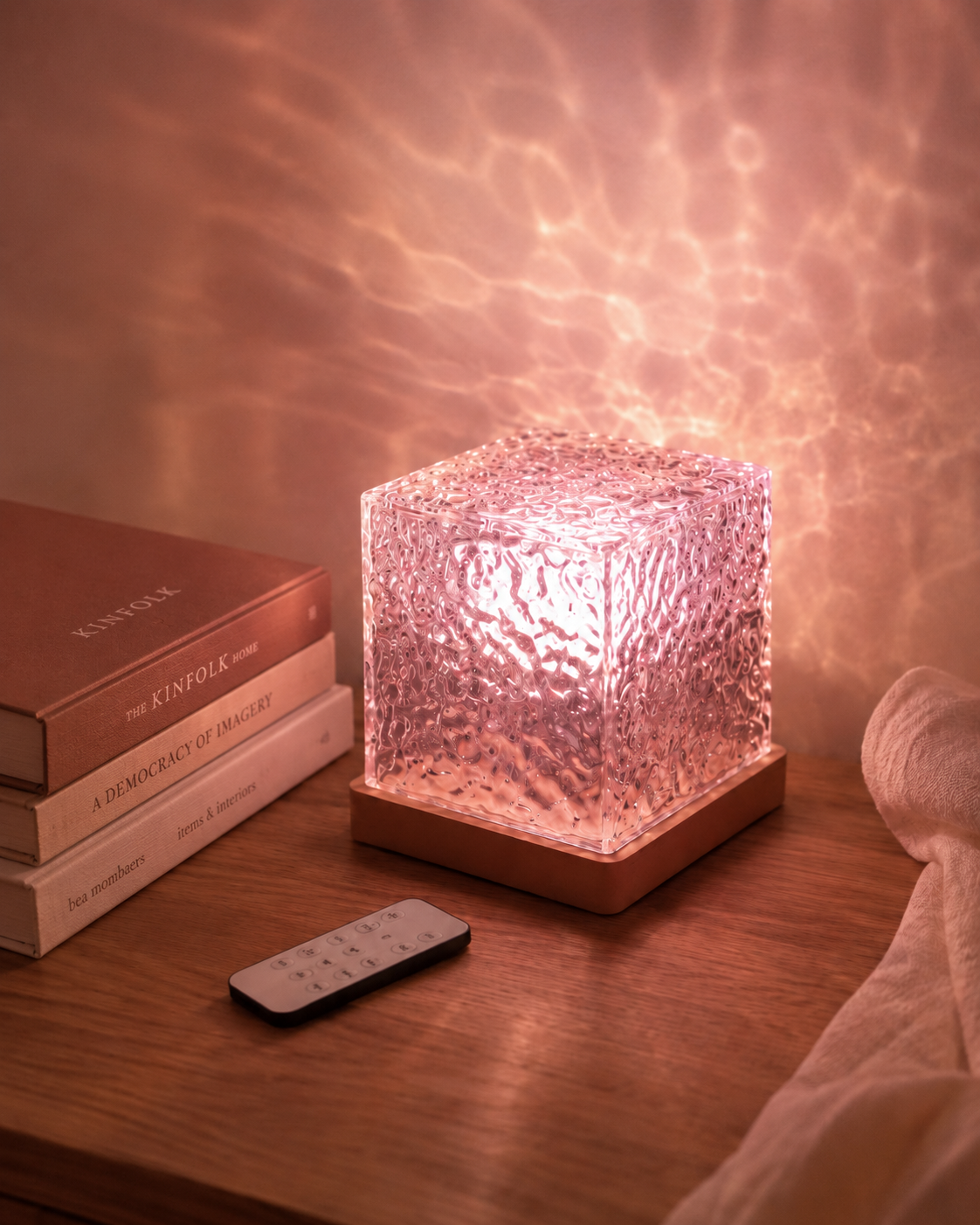 Ocean Night Light glowing pink on a bedside table with its remote control